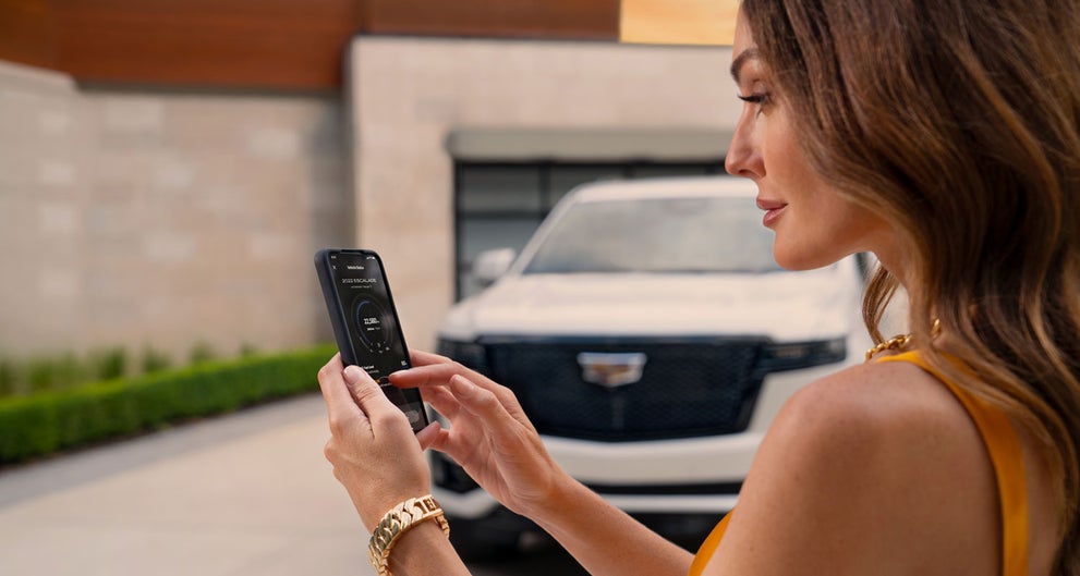 lady checking her mobile with a Cadillac vehicle background | Valley Cadillac in ROCHESTER NY